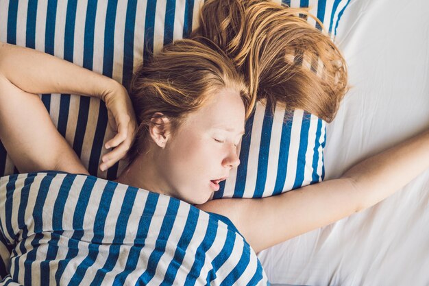 Bella giovane donna sdraiata a letto e dorme. Non dormire a sufficienza.