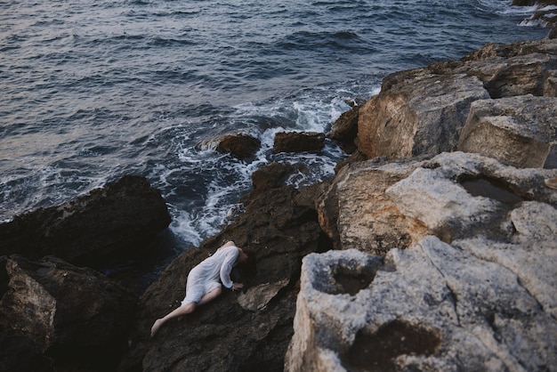 bella giovane donna sdraiata sulla costa rocciosa con crepe sulla superficie rocciosa inalterata foto di alta qualità