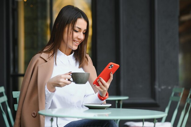 Bella giovane donna seduta al bar con una tazza di tè