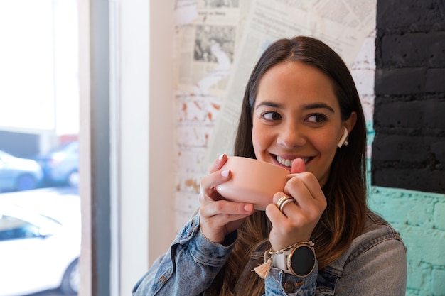 Bella giovane donna seduta in una caffetteria a bere il caffè