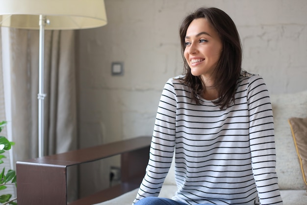 Bella giovane donna seduta sul divano, al chiuso.