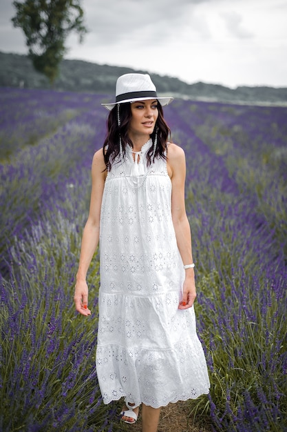 bella giovane donna sensuale con cappello e abito bianco sul campo di lavanda