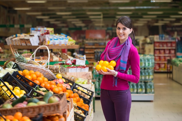 Bella giovane donna shopping per frutta e verdura nel reparto prodotti di un supermercato supermercato poco profondo nel profondo del campo