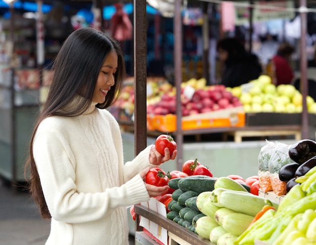 Bella giovane donna sorridente al mercato ortofrutticolo