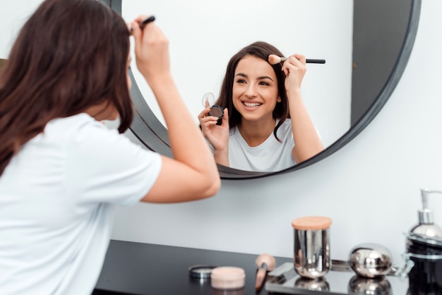 Bella giovane donna sorridente che fa il suo trucco