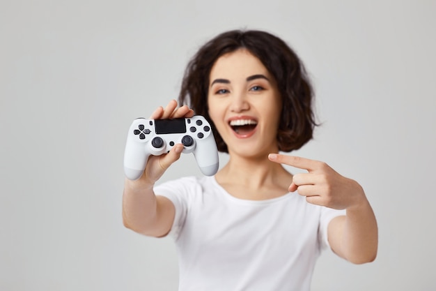 Bella giovane donna sorridente che mostra alla console per videogiochi. concentrati sulla console