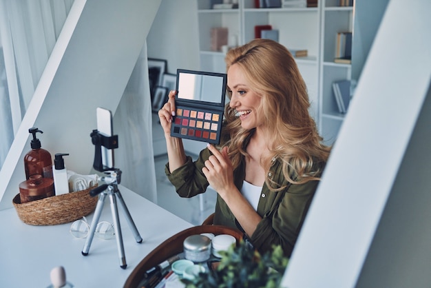 Bella giovane donna sorridente che vlogging su trucchi e prodotti di bellezza