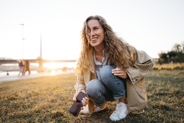 Bella giovane donna sorridente con il cellulare in strada