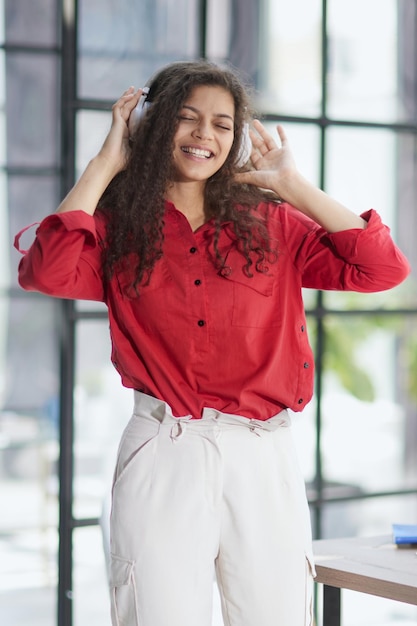 Bella giovane donna sorridente in cuffia in ufficio moderno