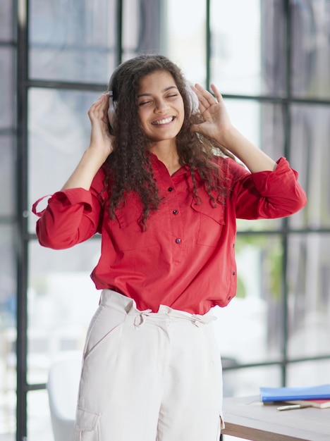 Bella giovane donna sorridente in cuffia in ufficio moderno