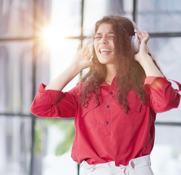 Bella giovane donna sorridente in cuffia in ufficio moderno