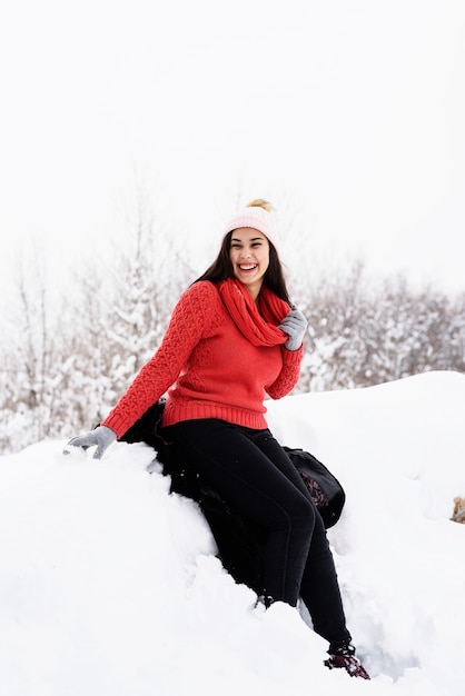 bella giovane donna sorridente seduto nel bosco innevato in inverno all'aperto