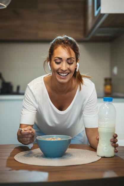 Bella giovane donna sorridente sta preparando la sua sana colazione nella sua cucina.