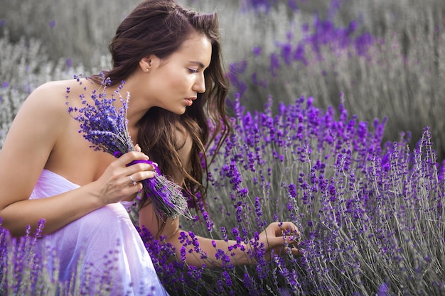 Bella giovane donna sul campo di lavanda. Concetto di aroma. Attraente giovane femmina all'aperto.