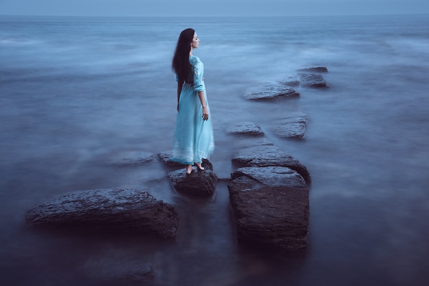 Bella giovane donna sul mare al crepuscolo. Lunga esposizione