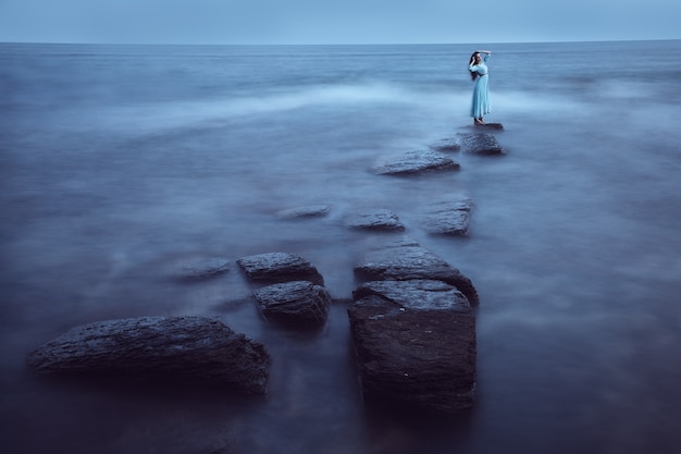 Bella giovane donna sul mare al crepuscolo. Lunga esposizione