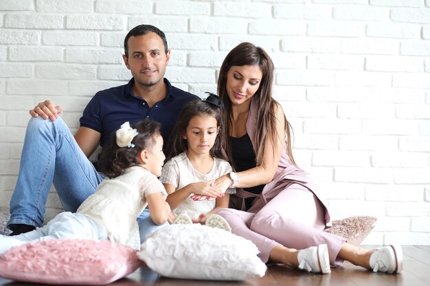 Bella giovane famiglia con figlie durante un servizio fotografico in uno studio bianco