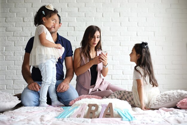 Bella giovane famiglia con figlie durante un servizio fotografico in uno studio bianco