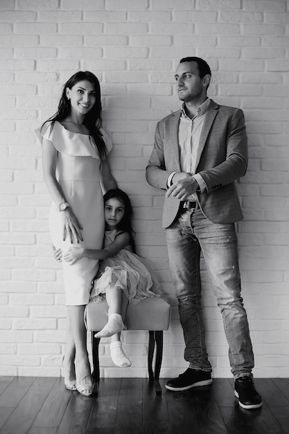 Bella giovane famiglia con figlie durante un servizio fotografico in uno studio bianco