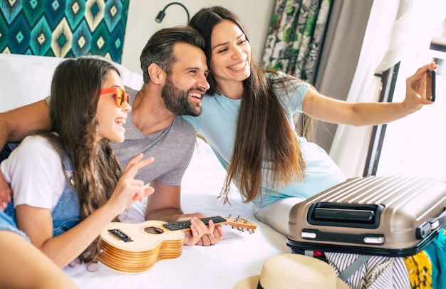 Bella giovane famiglia felice che fa selfie foto in camera da letto e divertirsi insieme