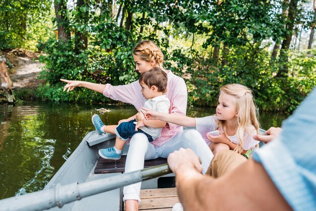 bella giovane famiglia in barca a cavallo sul lago e che punta da qualche parte al parco