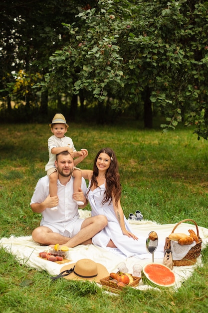bella giovane famiglia in bianco al picnic nel parco.