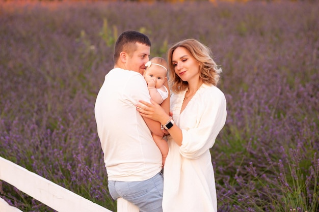 Bella giovane famiglia sul campo di lavanda fiore viola. Vacanze di famiglia