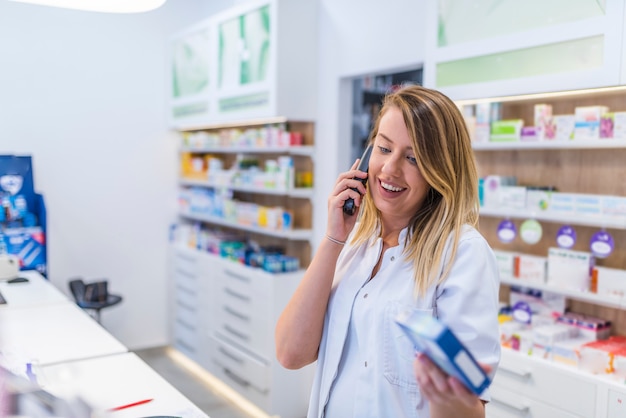 Bella giovane farmacista femmina parlando al telefono