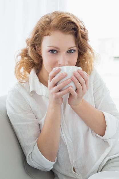 Bella giovane femmina e bere caffè a casa