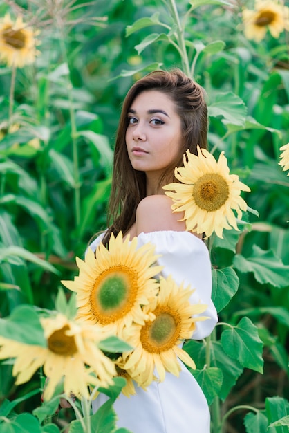 Bella giovane femmina per godersi la natura sul campo di girasoli al tramonto