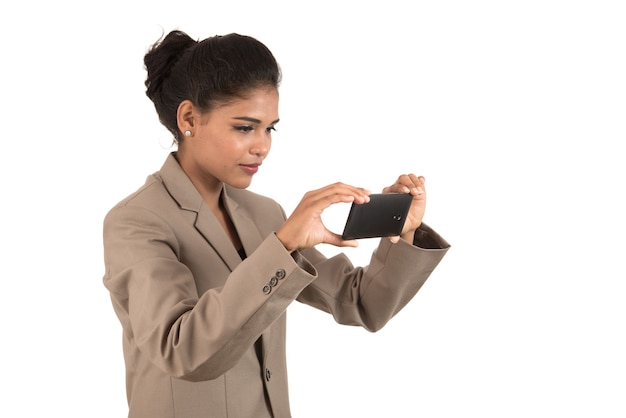 Bella giovane imprenditrice utilizza lo smartphone per scattare foto selfie isolato sul muro bianco