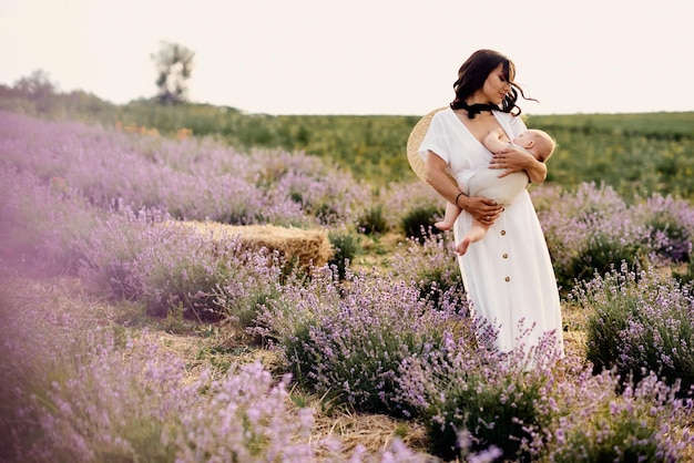 Bella giovane madre che allatta al seno il bambino in un campo di lavanda