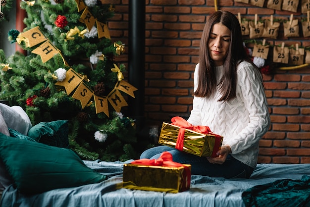 Bella giovane madre con il figlio carino vicino all'albero di Natale con i regali. buon Natale