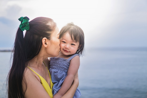 Bella giovane madre con la figlia sullo sfondo spiaggia