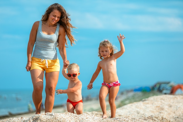 Bella giovane madre con un bambino che cammina lungo la riva del mare