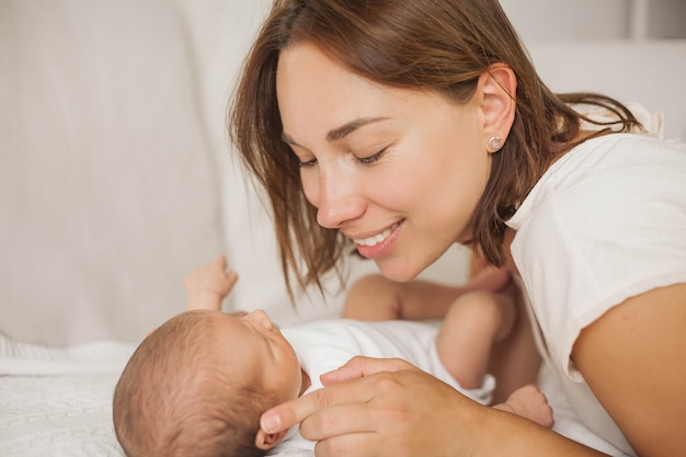 Bella giovane madre gioca con il bambino a letto. Maternità.