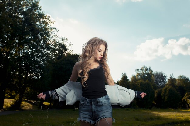 Bella giovane modella che indossa un abbigliamento casual e posa nel parco