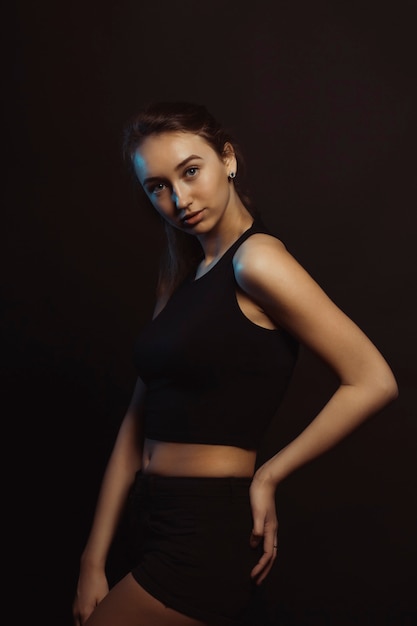 Bella giovane modella sexy in studio scuro con luce blu