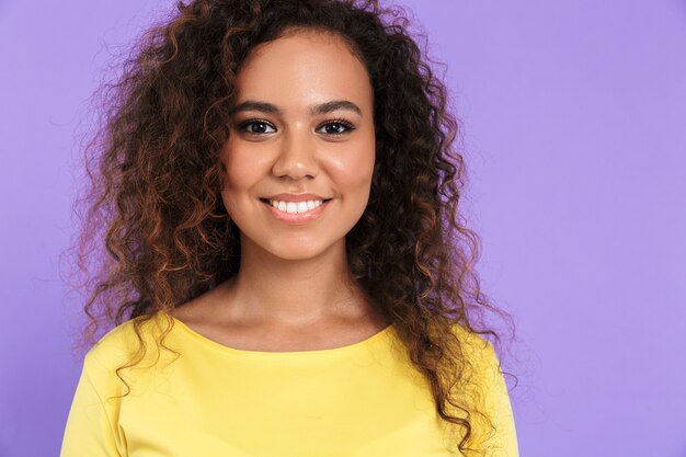 Bella giovane ragazza africana felice che indossa abiti casual in piedi isolato sul muro viola, guardando