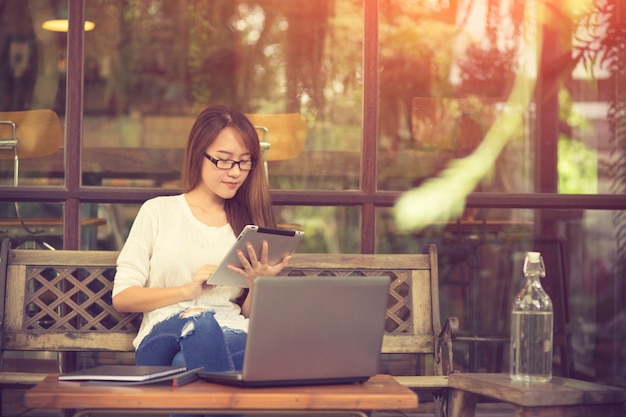 Bella giovane ragazza asiatica che lavora in una caffetteria con un computer portatile.