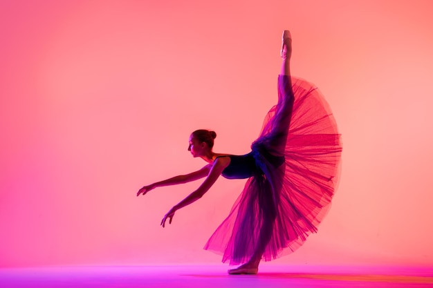 Bella giovane ragazza ballerina in scarpe da punta e una silhouette costume da bagno su uno sfondo rosso brillante.