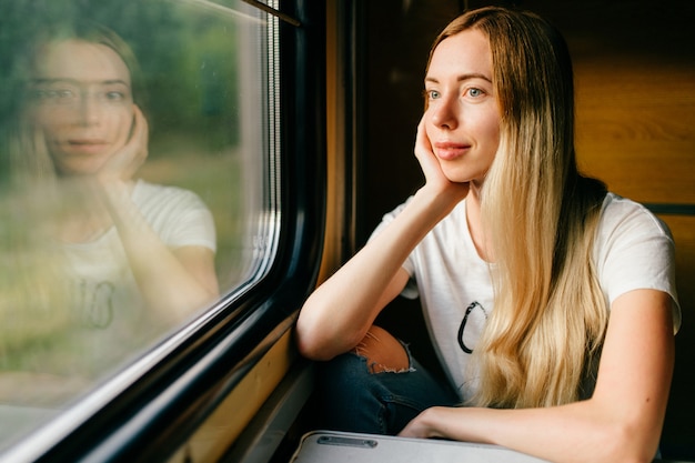 Bella giovane ragazza bionda che esamina finestra in treno