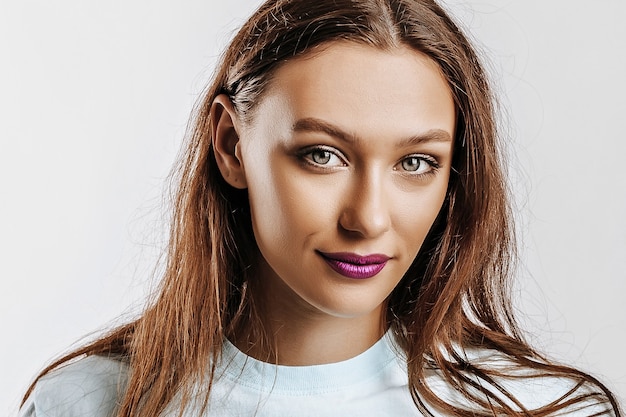 Bella giovane ragazza bruna con gli occhi verdi con i capelli lunghi con il trucco di moda con le labbra viola