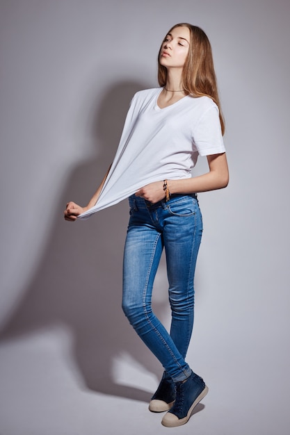 Bella giovane ragazza del modello di moda in blue jeans bianchi