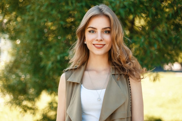 Bella giovane ragazza felice sorridente vicino a un albero in una giornata di sole estivo