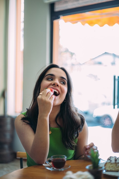 Bella giovane ragazza latina che mangia una fragola in un negozio di caffè.