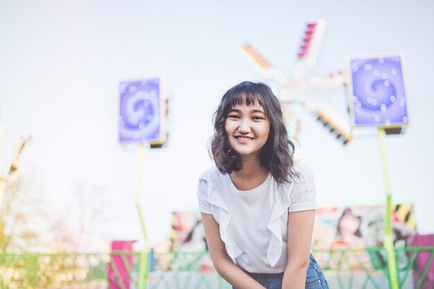 Bella giovane ragazza millenaria asiatica in un parco di divertimenti, sorridente. Copia spazio.