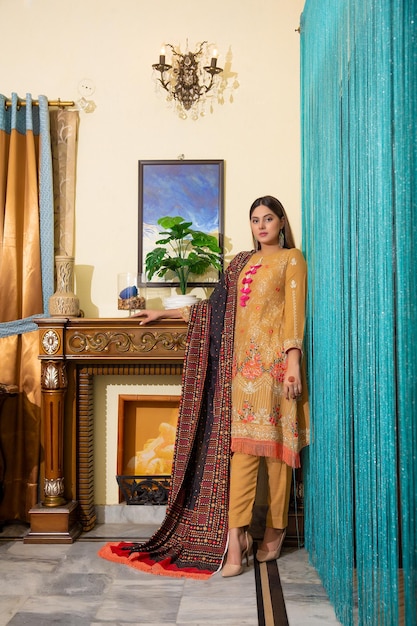 Bella giovane ragazza pakistana in piedi in una stanza per il servizio fotografico al coperto