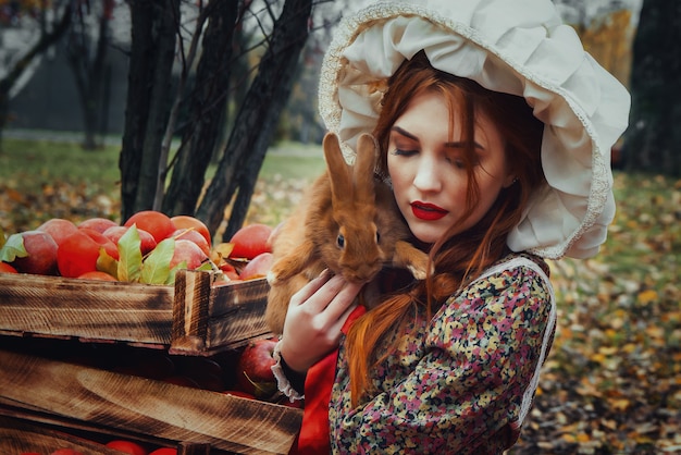 Bella giovane ragazza sexy con le mele rosse nel giardino di autunno