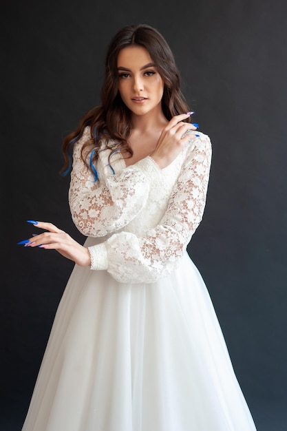 Bella giovane sposa femminile modello sexy con capelli scuri in splendido abito da sposa luce lungo lucido